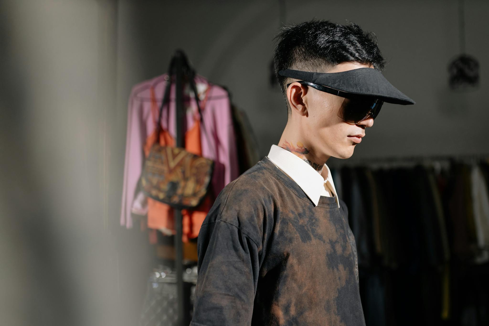 Fashion-forward man wearing a sun visor and sunglasses in a vintage clothing store.